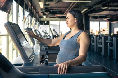 Spor salonunda koşu bandında hamile bir kadın. Sağlıklı spor yaşam tarzı. - Evet. Yüksek kalite fotoğraf