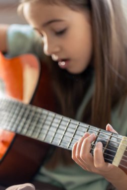 Kız gitar çalıyor. Gitarlı küçük bir kız. Yüksek kalite fotoğraf. Evde gitar çalıyorum. Küçük bir kız şarkı söyler ve gitar çalar..