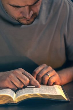 İncil okuyan bir adam. İncil 'e yakın çekimde erkek eli. Yüksek kalite fotoğraf. Din kavramı. Mesaj için yer var. Erkek eli İncil 'de.