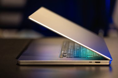 Karanlık arka planda yarı açık ekranı olan bir dizüstü bilgisayar. Yüksek kalite fotoğraf. Modern laptop. Ekran parlıyor..