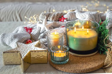 Sıcak bir Noel kompozisyonu, mumlar ve sıcak bir süveter. Noel konsepti. Yüksek kalite fotoğraf. Noel ağacı dallarıyla mum yakmak. Bulanık arkaplanda hafif bir çelenk.