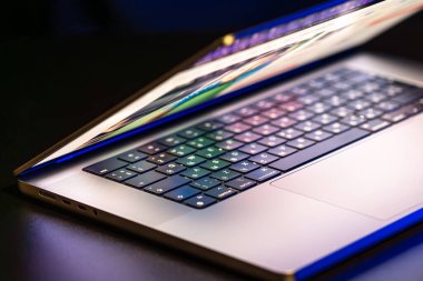 Karanlık arka planda yarı açık ekranı olan bir dizüstü bilgisayar. Yüksek kalite fotoğraf. Modern laptop. Ekran parlıyor..