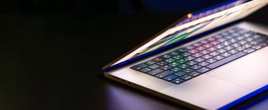 Karanlık arka planda yarı açık ekranı olan bir dizüstü bilgisayar. Uzayı kopyala Yüksek kalite fotoğraf. Modern dizüstü.