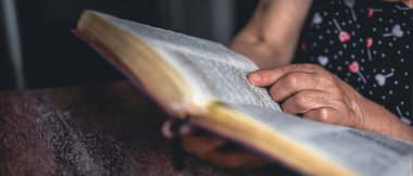 Yaşlı bir kadın İncil okur. Din kavramı. Yüksek kalite fotoğraf. Evde İncil okuyordum. İncil 'i olan yaşlı bir kadının elleri..