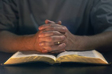 İncil okuyan bir adam. İncil 'e yakın çekimde erkek eli. Yüksek kalite fotoğraf. Din kavramı. Mesaj için yer var. Erkek eli İncil 'de.