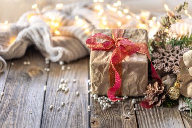 Noel kompozisyonu ve şenlikli bir hediye. Noel arkaplanı. Yüksek kalite fotoğraf. Sıcak bir süveterle Noel hediyesi. Metin için boşluklar. Ahşap bir arka planda samimi bir Noel kompozisyonu.
