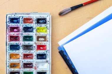 Suluboyalı palet. Suluboya ve boya fırçalı bir palet. Yüksek kalite fotoğraf. Yaratıcı bir kavram. Kemik ve kağıt ile suluboya.