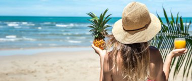 Egzotik bir sahilde ananaslı güzel bir kız. Denizde bir kadın. Yüksek kalite fotoğraf. Şapkalı bir kadın. Mesaj için yer. Denizin arka planında bir kadın.