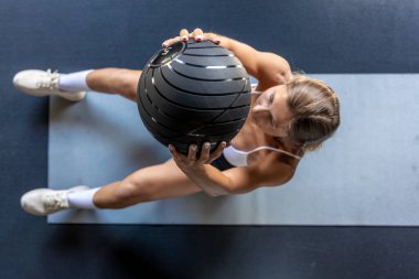 Sportif bir kız spor salonundaki paspasın üstünde topla egzersiz yapar. Spor egzersizleri ve sağlıklı yaşam tarzı kavramı. Yüksek kalite fotoğraf