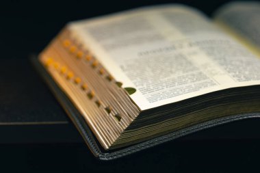 Siyah arka planda İncil 'i aç. Din kavramı. Yüksek kalite fotoğraf. Altın sayfalı İncil. Mesaj için yer var. İncil kitabına yakın çekim.