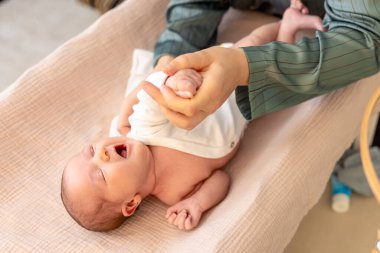 Anne bebeğine kıyafet giyiyor. Bebek sağlığı hijyen konsepti. Yüksek kalite fotoğraf. Yeni doğmuş bebek. Yatakta yatarken.