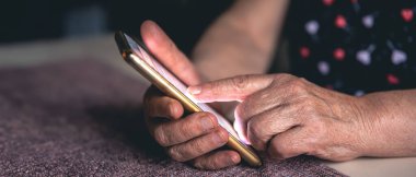 Telefonu olan yaşlı bir kadın. Telefonu olan yaşlı bir kadının elleri. Yüksek kalite fotoğraf. Mesaj için yer var. Yaşlı kadın telefonda bir mesaj yazıyor..