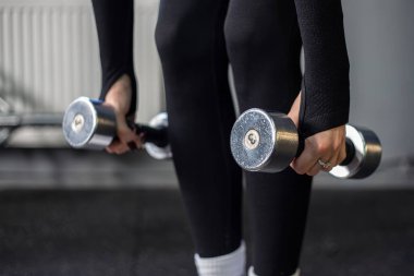 Spor salonundaki genç kadın. Spor salonunda dambıllar. Spor salonu. Yüksek kalite fotoğraf. Salondaki dambılı kız. Boşluğu kopyala.