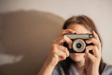 Klasik fotoğraf makinesi olan genç bir kadın. Kız bir film kamerasında fotoğraf çekiyor. Yüksek kalite fotoğraf. Mesaj için yer var. Hafif bir arkaplanda. Retro kamera.
