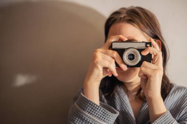 Klasik fotoğraf makinesi olan genç bir kadın. Kız bir film kamerasında fotoğraf çekiyor. Yüksek kalite fotoğraf. Mesaj için yer var. Hafif bir arkaplanda. Retro kamera.