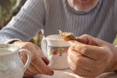 Yaşlı bir adam sandviç yiyor. Sandviç yakın plan. Yüksek kalite fotoğraf. Yaşlı erkek elleri ve bir sandviç..