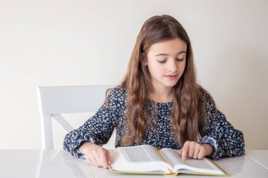 Evde kitap okuyan mutlu kız. Kız okulda ders için hazırlanıyor. Yüksek kalite fotoğraf. Bir kız ve bir kitap.