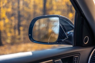 Bir arabanın dikiz aynası. Dikiz aynasından görüldü. Yüksek kalite fotoğraf. Seyahat konsepti. Araba ve ayna. Yolculuk. Sonbahar mevsimidir. Sonbahar yaprakları.