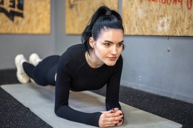 Genç kadın spor salonunda egzersiz yapıyor. Vücut kaslarını sağlıklı yaşam konseptine uydurmak için birebir spor. Yüksek kalite fotoğraf. Kadın ve kas için şınav çeken antrenman..