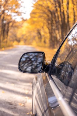 Bir arabanın dikiz aynası. Dikiz aynasından görüldü. Yüksek kalite fotoğraf. Seyahat konsepti. Araba ve ayna. Yolculuk. Sonbahar mevsimidir. Sonbahar yaprakları.