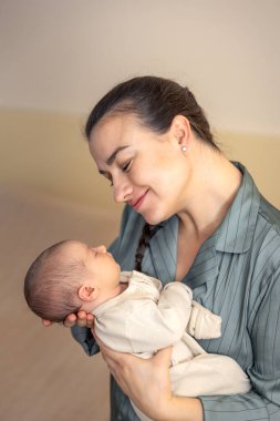 Yeni doğmuş bir bebeği olan genç bir anne. Yeni doğmuş bebek. Yüksek kalite fotoğraf. Annelik. Anne ve bebek evde. Bir anne yeni doğmuş bir bebeği kollarında tutar..