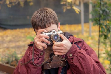 Genç bir adam eski bir kamerayla fotoğraf çekiyor. Film kamerası fotoğrafçılığı. Yüksek kalite fotoğraf. Adamın biri sokaktaki klasik bir film kamerasıyla fotoğraf çekiyor. Bir adam elinde antika bir kamera tutuyor..
