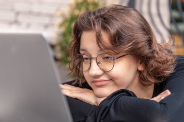 Dizüstü bilgisayarla çalışan üzgün ve yorgun genç bir kadın. Duygu konsepti. Yüksek kalite fotoğraf. Gözlüklü bir kız dizüstü bilgisayarda çalışmaktan yoruldu..