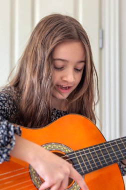 Kız evde gitar çalıyordu. Kız ve gitar. Yüksek kalite fotoğraf. Kız gitar çalıyor ve şarkılar söylüyor. Yakın plan. Yaylı bir enstrüman çalmak.