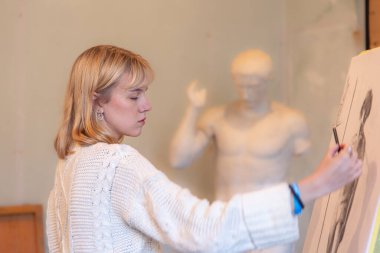 Stüdyoda resim yapan genç bir kadın sanatçı. Sanat konsepti. Bir kadın çiziyor. Yüksek kalite fotoğraf. Bir kadın atölyesinde kağıt üzerine kalem çizer. Kalem çizimi.