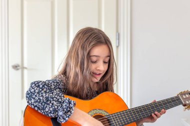 Kız evde gitar çalıyordu. Kız ve gitar. Yüksek kalite fotoğraf. Kız gitar çalıyor ve şarkılar söylüyor. Yakın plan. Yaylı bir enstrüman çalmak.