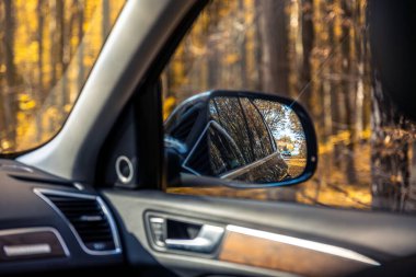 Bir arabanın dikiz aynası. Dikiz aynasından görüldü. Yüksek kalite fotoğraf. Seyahat konsepti. Araba ve ayna. Yolculuk. Sonbahar mevsimidir. Sonbahar yaprakları.