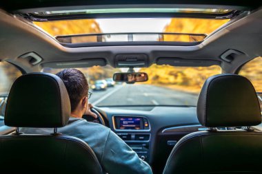 Asfalt yolda modern araba kullanmak. Genç bir adam araba kullanıyor. Yüksek kalite fotoğraf. Araba kullanırken direksiyonu tutan genç adam. Yolculuk. Yerel seyahat konsepti. Maceraya susamışım..