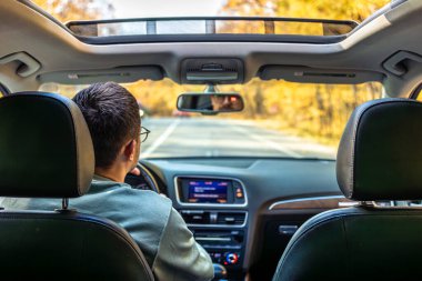 Asfalt yolda modern araba kullanmak. Genç bir adam araba kullanıyor. Yüksek kalite fotoğraf. Araba kullanırken direksiyonu tutan genç adam. Yolculuk. Yerel seyahat konsepti. Maceraya susamışım..