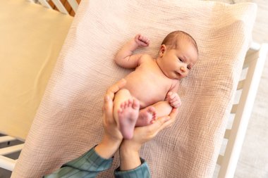 Ebeveynler yeni doğmuş bir bebeğin ayaklarına sarılmış. Annem bebek ayağı tutuyor. Yüksek kalite fotoğraf. Yeni doğmuş bir bebek yatakta yatıyor. Yeni doğmuş bebek.