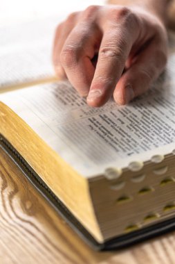 İncil 'e yakın çekim. Kutsal Kitap İncili. İncil okuyan bir adam. Yüksek kalite fotoğraf. Erkek eli İncil 'de, okuyor. Hıristiyanlık ve din kavramı. Yaşlı buruşuk erkek elleri.