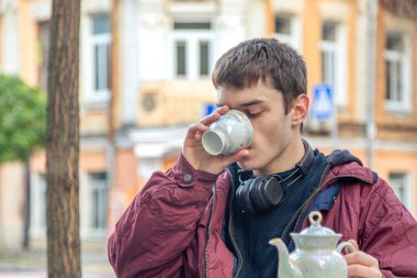 Şehirde çay içen yakışıklı bir adam. Bir adam kafede çay içiyor. Yüksek kalite fotoğraf. Nadir bulunan bir çaydanlık. Şehirdeki her gün..