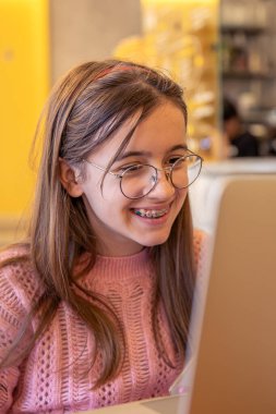 An interested teenage girl studies in an online school. High quality photo. Learning concept. Emotion concept. The girl studies using a laptop. clipart