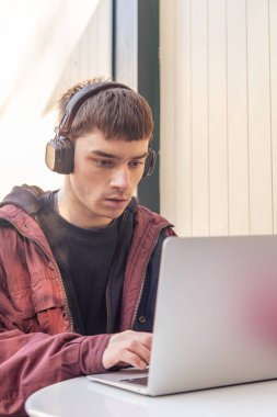 Bir öğrenci dizüstü bilgisayar kullanarak ders çalışıyor. İnternette okuyan erkek öğrenci. Öğrenme konsepti. Yüksek kalite fotoğraf. Üniversitede ya da üniversitede okuyan ve dizüstü bilgisayarda ödev yapan genç bir öğrenci..