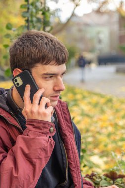 Genç bir erkek öğrenci telefonda konuşuyor. Teknoloji konsepti. Yüksek kalite fotoğraf. Yakışıklı genç bir erkek öğrenci ailesiyle telefonda konuşuyor..