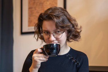 Elinde kahve olan üzgün bir kız. Duygu konsepti. Üzüntü duygusu. Yüksek kalite fotoğraf. Bardaklı bir kız kahvecide eğleniyor..