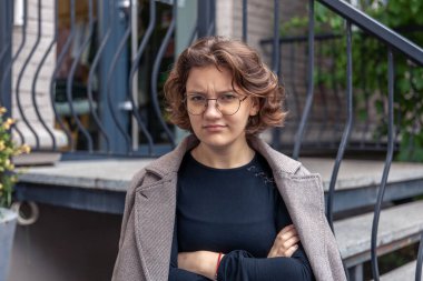 Kızgın genç bayan, yakın plan. Duygu konsepti. Öfke duygusu. Yüksek kalite fotoğraf. Gözlüklü bir kız kızgın ve kameraya bakıyor..