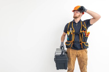 Erkek müteahhit. Tulumlu ve kasklı elektrik mühendisi alet çantasını elinde tutuyor. Hafif arkaplan. İnşaat konsepti. Mesaj için yer var. Yüksek kalite fotoğraf.