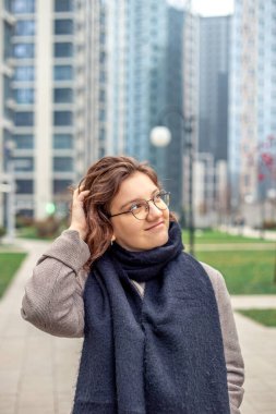 Büyük bir şehirde genç bir kadının portresi. Şehirdeki kadın. Yüksek kalite fotoğraf. Şehirde güzel, gülümseyen bir kadın. Şehirde bir yürüyüş. Metin için boşluk.