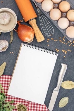 Boş defterle malzemeler pişiriyorum. Şifalı bitkiler ve baharatlarla dolu bir yemek tarifi kitabı. Yüksek kalite fotoğraf. Uzayı kopyala Üst manzara, düz yatış. Yemek pişirme hazırlığı.