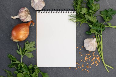 Boş defterle malzemeler pişiriyorum. Şifalı bitkiler ve baharatlarla dolu bir yemek tarifi kitabı. Yüksek kalite fotoğraf. Uzayı kopyala Üst manzara, düz yatış. Yemek pişirme hazırlığı.
