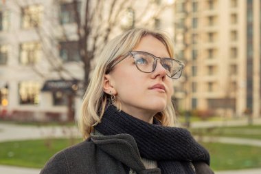 Büyük bir şehirde güzel bir genç kadının portresi. Büyük şehirde bir kadın. Yüksek kalite fotoğraf. Gözlüklü sarışın kadın. Sonbahar sezonu. Şehirde bir yürüyüş..