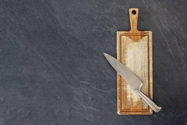 Bıçak manzaralı tahta kesme tahtası. Yemek pişirme konsepti. Yüksek kalite fotoğraf. Bıçaklı bir kesme tahtası, üst manzara. Uzayı kopyala Koyu arkaplan.