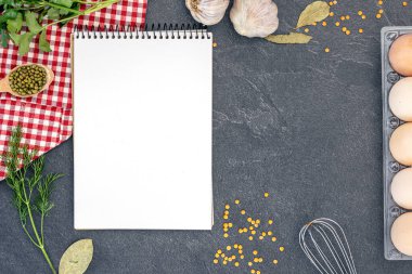 Boş defterle malzemeler pişiriyorum. Şifalı bitkiler ve baharatlarla dolu bir yemek tarifi kitabı. Yüksek kalite fotoğraf. Uzayı kopyala Üst manzara, düz yatış. Yemek pişirme hazırlığı.