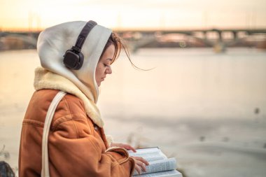 Genç bir kadın İncil 'i doğada okur. Hıristiyanlık, inanç ve dua. Yüksek kalite fotoğraf. Elinde İncil tutan bir kadın. Kutsal İncil 'e tapmak ve okumak. Boşluğu kopyala.