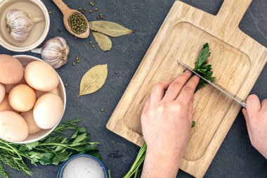 Ahşap kesme tahtasıyla maydanoz kesen kadın eller. Yemek malzemeleriyle donatılmış bir geçmiş. Yüksek kalite fotoğraf. Üst manzara, düz uzanma.